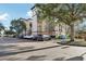 View of the building complex with parking, mature landscaping, and blue sky at 12527 Floridays Resort Dr # E-111, Orlando, FL 32821