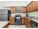 A full kitchen with stainless steel appliances, wooden cabinets, and tile flooring at 12527 Floridays Resort Dr # E-111, Orlando, FL 32821