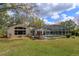 Backyard featuring a white house, screened pool, and well-maintained lawn at 1322 Ensenada Dr, Orlando, FL 32825