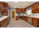 Eat-in kitchen with wooden cabinetry, stainless appliances, tile floors and an open doorway at 1322 Ensenada Dr, Orlando, FL 32825