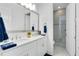 Bright bathroom features a double vanity with white cabinets, granite counters, large mirror and walk-in glass shower at 13346 Alderley Dr, Orlando, FL 32832