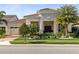 Elegant home boasts a stone facade, tiled roof, arched entry, and lush landscaping for exceptional curb appeal at 13346 Alderley Dr, Orlando, FL 32832