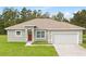 Charming single-story home with a well-maintained lawn, attached garage, and a welcoming red front door at 14750 Sw 63Rd Ter, Ocala, FL 34473