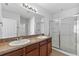 Bathroom with a double sink vanity, granite counters, and a glass-enclosed shower at 16140 Yelloweyed Dr, Clermont, FL 34714