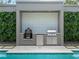Modern outdoor kitchen with a built-in grill and mini-fridge, perfect for outdoor entertaining by the pool at 1970 Laurel Rd, Winter Park, FL 32789