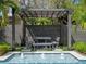 The pool area features a dining space under a pergola with a table and benches by the fountain at 1970 Laurel Rd, Winter Park, FL 32789