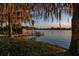 Idyllic waterfront backyard with a private dock, lush landscaping, and serene lake views at 2020 Venetian Way, Winter Park, FL 32789