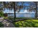 Scenic backyard view of a lake and dock with a bench on a sunny day at 2020 Venetian Way, Winter Park, FL 32789