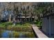Lakeside backyard view with a boat dock, walkway, and mature trees covered in Spanish moss at 2020 Venetian Way, Winter Park, FL 32789