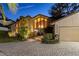 Stunning home exterior featuring stone accents, large windows, lush landscaping, and a paver driveway at 2020 Venetian Way, Winter Park, FL 32789