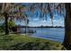 Waterfront view showing a private dock, boat lift, and moss-draped trees at the water's edge at 2020 Venetian Way, Winter Park, FL 32789