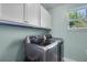 Well-lit laundry room with white cabinets, stacked washer and dryer, and a window offering natural light at 2109 E Central Blvd, Orlando, FL 32803