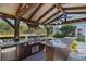 Outdoor kitchen with stainless steel grill, granite countertops, a mini-fridge, a fan, and wood beams at 2109 E Central Blvd, Orlando, FL 32803