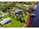 Aerial view of waterfront home with covered boathouse, lush lawn, patio, and landscaping, including mature palms and trees at 2112 Shady Ln, Geneva, FL 32732