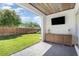 Outdoor patio with brick flooring, wooden cabinets, television, and view of the fenced green backyard at 2536 Brookshire Ave, Winter Park, FL 32792