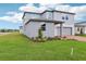Side view of a modern two-story home showcasing a well-maintained lawn and a neutral color palette at 2933 Wild Olive Dr, St Cloud, FL 34772