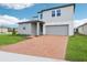 A modern two-story home with a brick driveway, a gray two-car garage, and manicured landscaping at 2933 Wild Olive Dr, St Cloud, FL 34772