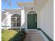 Close-up of the front entrance, featuring a green door, arched window, and landscaped surroundings at 3275 Deer Lick Ct, Kissimmee, FL 34746