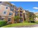 Low angle of multi-story condo building with exterior balcony, neutral colors, and manicured landscaping at 3332 Robert Trent Jones Dr # 20703, Orlando, FL 32835