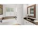 Elegant primary bathroom featuring a soaker tub, granite countertop vanity, and window with light-filtering shutters at 3352 Park Grove Ct, Longwood, FL 32779