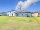 Spacious backyard view to home, featuring healthy green grass, trees, and fenced perimeter with other homes at 338 Crestwind Dr, Daytona Beach, FL 32124