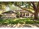 Charming single-story home featuring an arched entryway, lush landscaping and a large tree at 3415 Starbird Dr, Ocoee, FL 34761