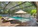 Relaxing screened-in pool area with brick pavers, an umbrella, and chaise lounges, perfect for summer at 3415 Starbird Dr, Ocoee, FL 34761
