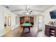 Open living room with brick fireplace, a billiard table, wood floor and white ceiling beams at 650 N 4Th Ave, Deltona, FL 32725