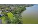 An aerial view of a lakeside property with a lush lawn and mature trees lining the shore at 703 Valencia Shores Dr, Winter Garden, FL 34787
