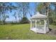 White gazebo with intricate details stands in a lush green lawn, offering a peaceful retreat at 703 Valencia Shores Dr, Winter Garden, FL 34787