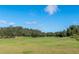 A picturesque golf course with lush green fairways and mature trees on a clear, sunny day at 7928 Hanson Bay Pl, Kissimmee, FL 34747
