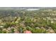 Aerial view of a residential area, highlighting lush trees and houses with red tiled roofs at 106 Waterwood Dr, Yalaha, FL 34797