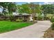 Charming single-story home with lush landscaping and a paved driveway surrounded by mature trees at 106 Waterwood Dr, Yalaha, FL 34797