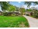 Charming single-story home with lush landscaping and a paved driveway surrounded by mature trees at 106 Waterwood Dr, Yalaha, FL 34797