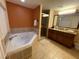 A bathroom showcasing a soaking tub, walk-in shower, granite countertops, and dark wood cabinets at 12544 Floridays Resort Dr # 102, Orlando, FL 32821