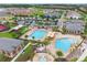 An aerial shot shows a community pool and splashpad, parking area, manicured landscape and colorful homes at 13628 Abberwick Dr, Orlando, FL 32832