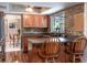 This is a kitchen with brown wooden cabinets, brick backsplash, and a kitchen island with two wooden chairs at 1404 Barcelona Ct, Winter Springs, FL 32708
