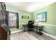 Home office has gray wood floors, green walls, window with blinds, a desk and rolling chair at 1404 Barcelona Ct, Winter Springs, FL 32708