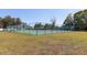 Well-maintained outdoor tennis court with green surface, surrounded by secure fencing and greenery at 1404 Barcelona Ct, Winter Springs, FL 32708