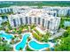 Aerial view of a condo complex with multiple pools, lush landscaping, and a beautiful lakeside backdrop at 14501 Grove Resort Ave # 3601, Winter Garden, FL 34787