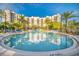 Inviting pool area with comfortable lounge chairs, palm trees, and a multi-story condo building in the background at 14501 Grove Resort Ave # 3601, Winter Garden, FL 34787