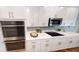 Kitchen with stainless steel appliances, including double ovens and white cabinets, and mosaic backsplash at 2050 1St Ave, Deland, FL 32724