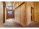 Long hallway featuring wood paneling, vaulted ceiling, and outdated carpeting leading to main door at 220 Wekiva Park Drive, Sanford, FL 32771