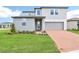 Two-story home with gray siding, brick driveway, manicured lawn, and integrated two-car garage at 2917 Wild Olive Dr, St Cloud, FL 34772