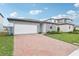 Stylish single-Gathering home with a brick driveway, modern gray siding, and a well-maintained lawn at 2929 Wild Olive Dr, St Cloud, FL 34772