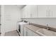 Functional laundry room featuring modern washer, dryer, sink, and white cabinets at 3347 Hanging Tide St, Winter Garden, FL 34787