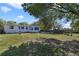 Large backyard featuring a white house, storage shed and a vast grassy area with mature trees at 5719 Meridian Way, Orlando, FL 32808