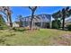 Backyard view showing the home's screened-in pool area and expansive lawn surrounded by mature trees at 5776 Falling Tree Ln, Port Orange, FL 32127