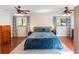 Spacious main bedroom with hardwood floors, two windows with curtains, and two ceiling fans at 643 Woodridge Dr, Fern Park, FL 32730