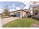 View of garage and driveway; includes pavers, landscaping, and exterior wall with light fixtures at 7112 Enchanted Lake Dr, Winter Garden, FL 34787